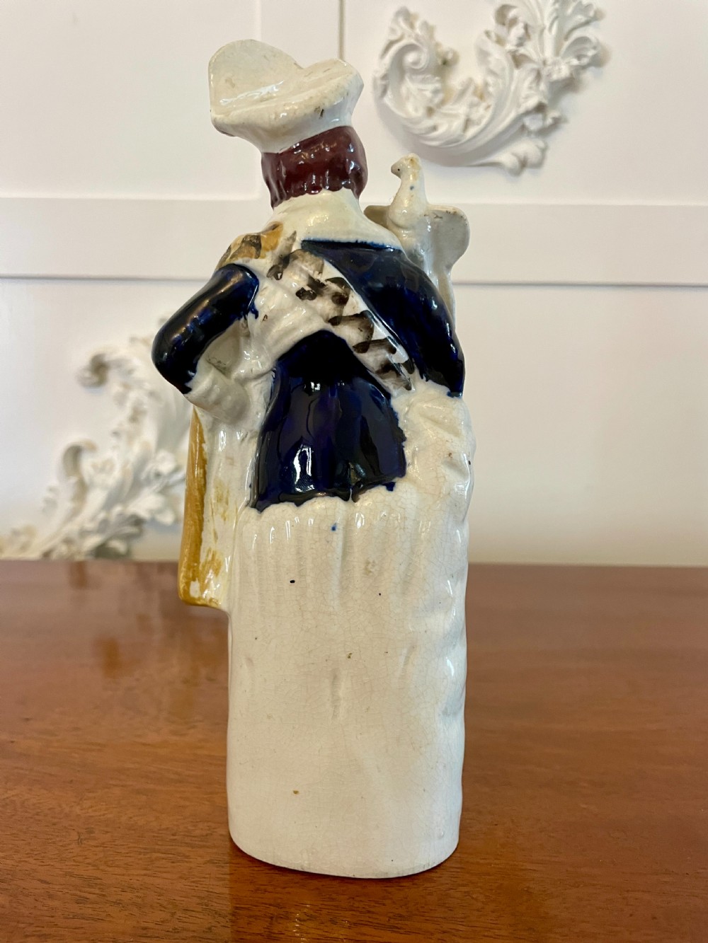A Victorian Staffordshire earthenware flatback figure depicting a male standing character with a bird perched on his gloved hand, decorated in blue, green, orange, and white enamels. View IX