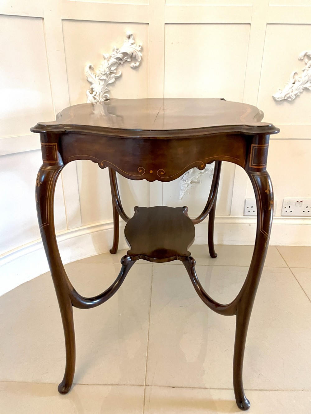 A Victorian mahogany centre table featuring a shaped serpentine top with floral marquetry inlay, slender cabriole legs, and a lower undertier. View V