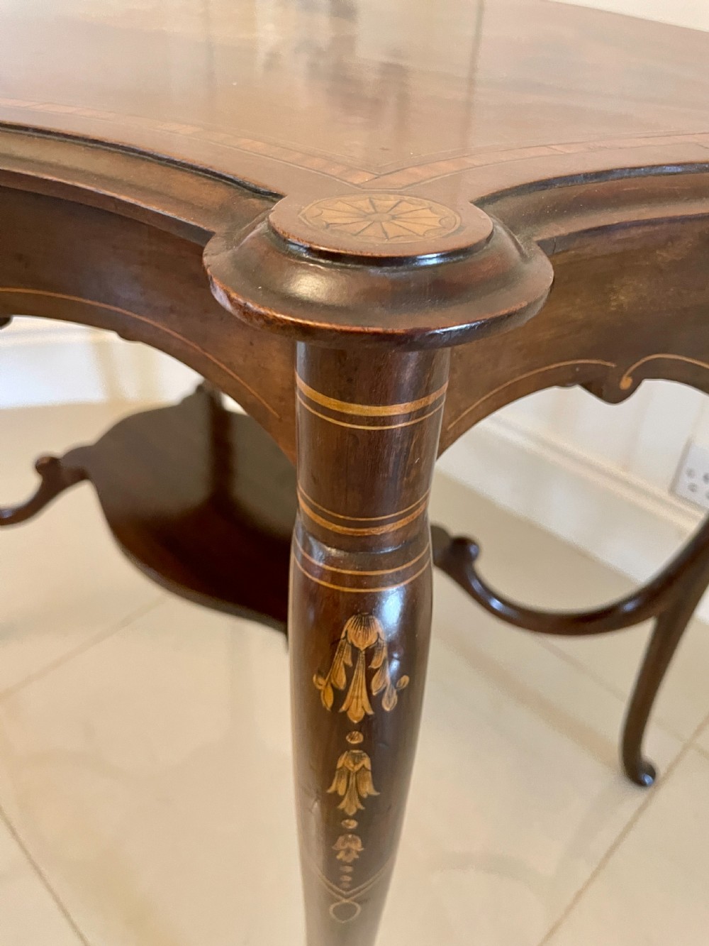 A Victorian mahogany centre table featuring a shaped serpentine top with floral marquetry inlay, slender cabriole legs, and a lower undertier. View VI