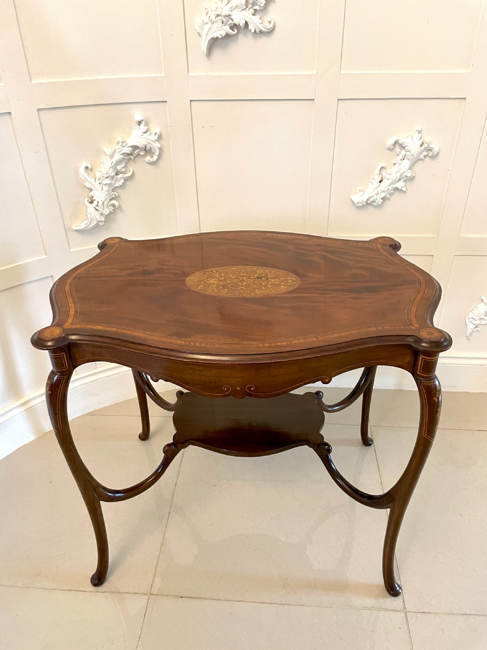A Victorian mahogany centre table featuring a shaped serpentine top with floral marquetry inlay, slender cabriole legs, and a lower undertier. View XII