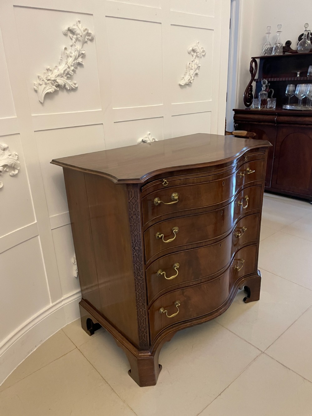 An Edwardian mahogany chest of drawers with a serpentine curved front, four graduated drawers, brass swan-neck handles, and bracket feet. View II