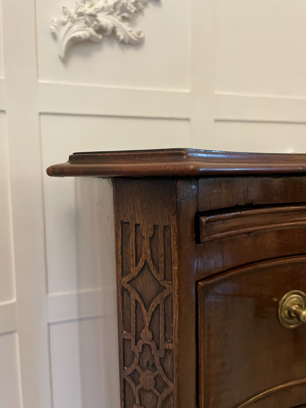 An Edwardian mahogany chest of drawers with a serpentine curved front, four graduated drawers, brass swan-neck handles, and bracket feet. View VI