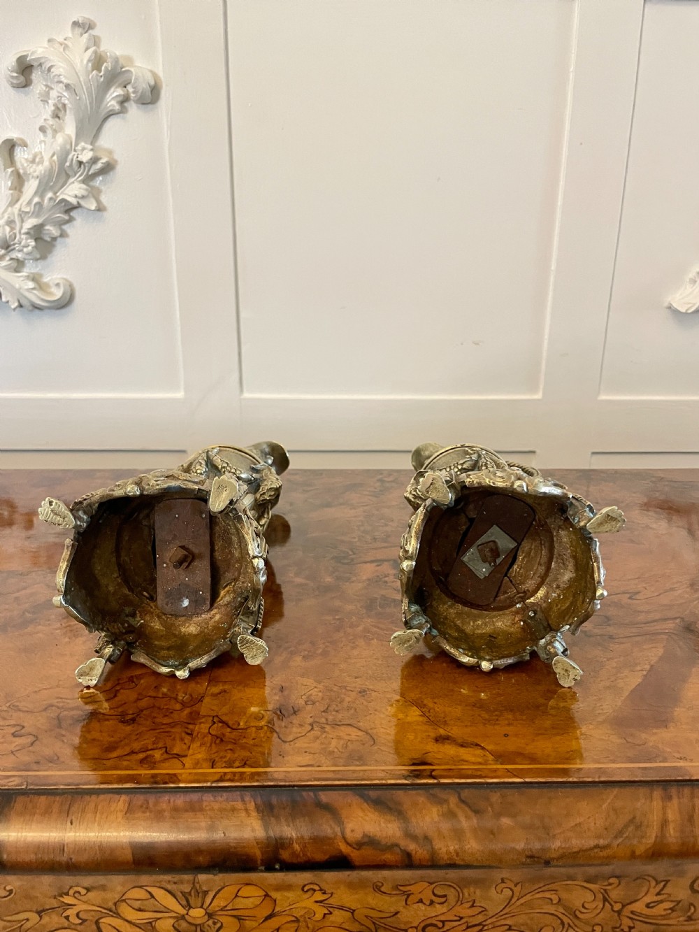 A matching pair of ornate Victorian brass ewers with decorative scroll handles, leaf motifs, and footed bases resting on a polished timber surface. View II