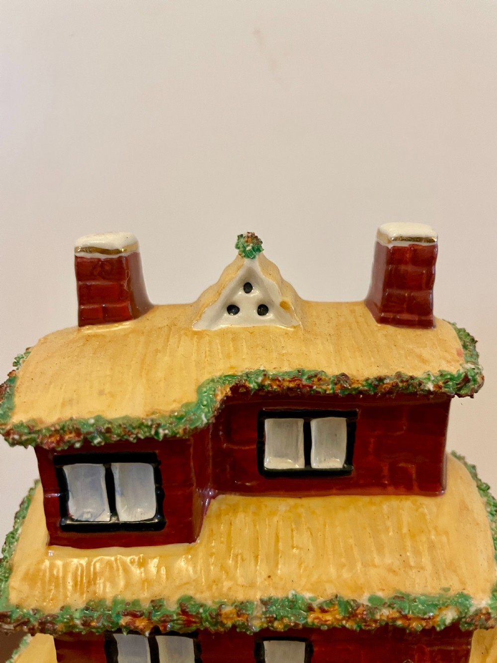 A Victorian Staffordshire pottery flatback figurine depicting a multi-storey terracotta red house with a yellow thatched roof, green encrusted foliage trim, and two chimneys. View V