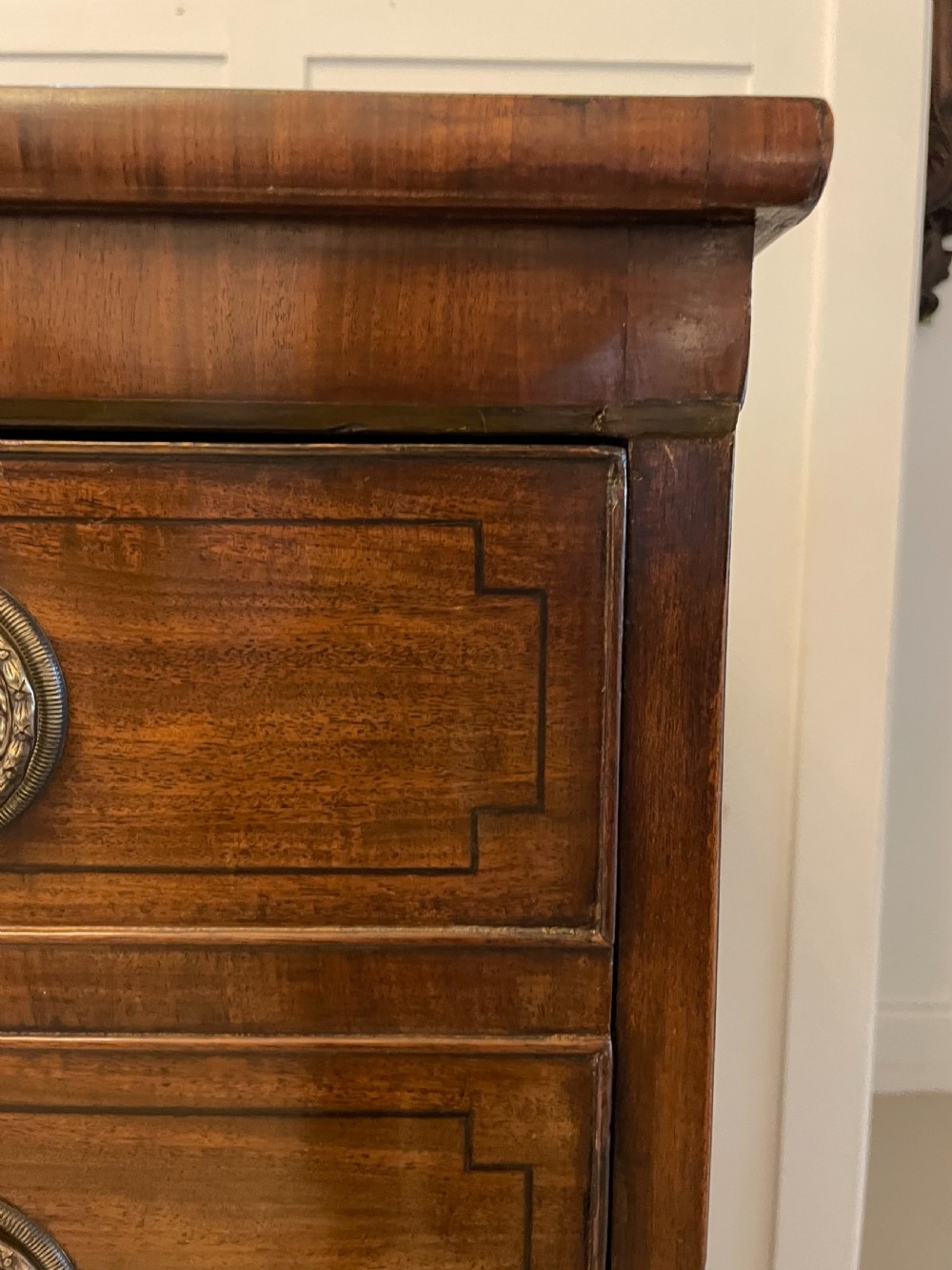 A George III mahogany secretaire desk featuring top drawers with brass ring handles over a two-door panelled cupboard base resting on bracket feet. View III