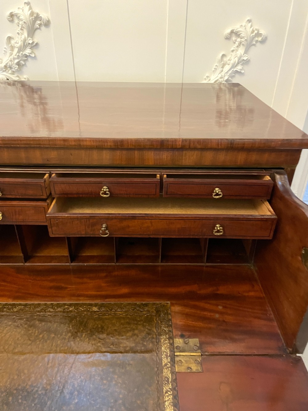 A George III mahogany secretaire desk featuring top drawers with brass ring handles over a two-door panelled cupboard base resting on bracket feet. View XV