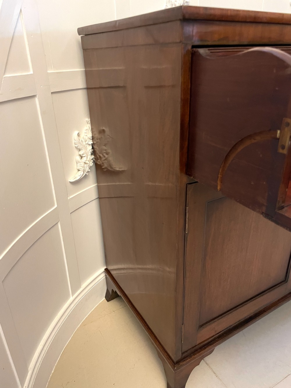 A George III mahogany secretaire desk featuring top drawers with brass ring handles over a two-door panelled cupboard base resting on bracket feet. View XVII