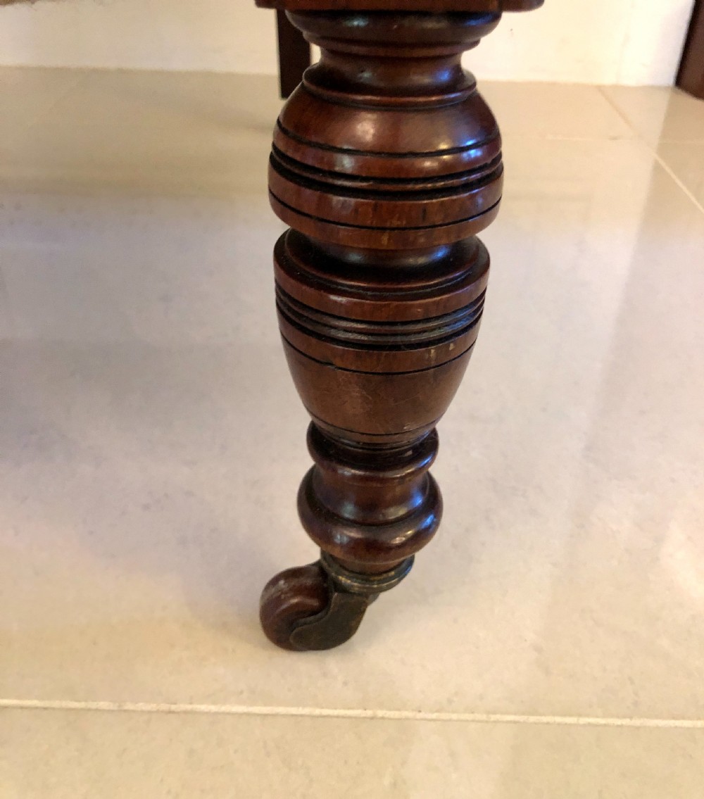 A Victorian carved walnut ladies chair featuring blue and white floral fabric upholstery, turned front legs with castors, and a spindle crest rail. View V
