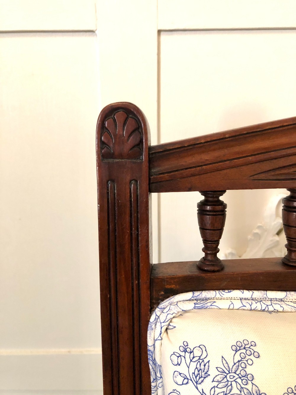 A Victorian carved walnut ladies chair featuring blue and white floral fabric upholstery, turned front legs with castors, and a spindle crest rail. View X