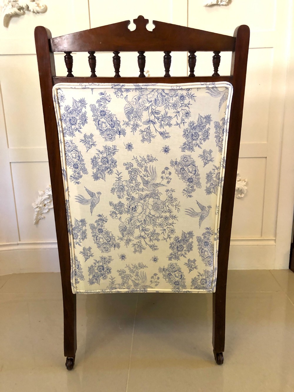 A Victorian carved walnut ladies chair featuring blue and white floral fabric upholstery, turned front legs with castors, and a spindle crest rail. View XII