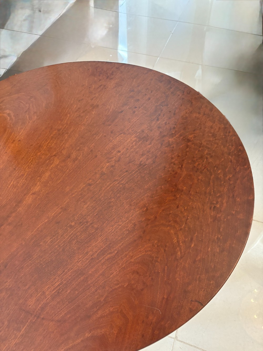A George III circular plum pudding mahogany tilt-top table shown tilted vertically on a turned column stem with tripod legs. View II