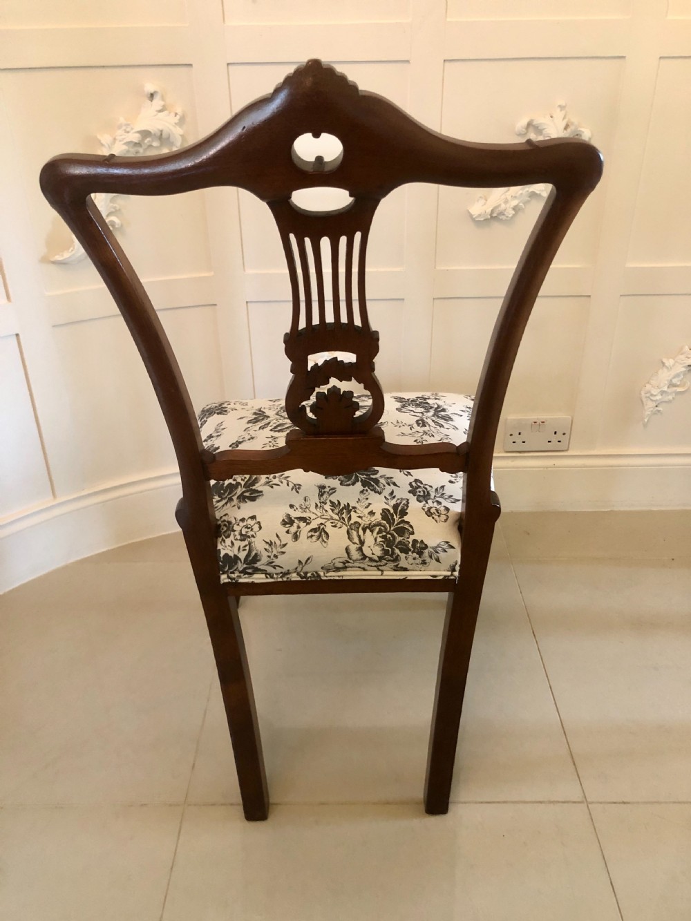 A set of four dark mahogany Victorian dining chairs featuring openwork carved back splats, cabriole front legs, and seats upholstered in a monochrome floral fabric. View III