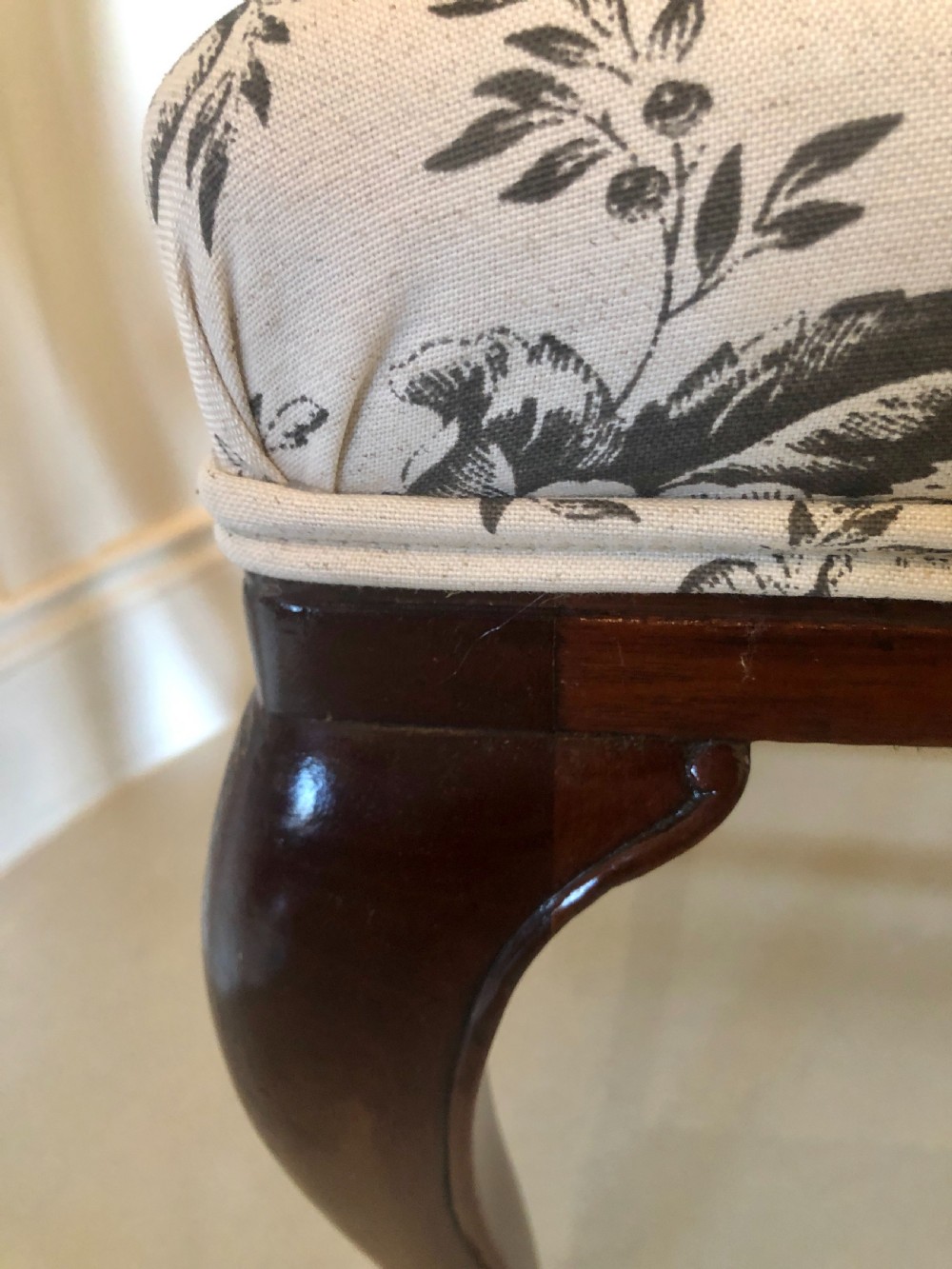 A set of four dark mahogany Victorian dining chairs featuring openwork carved back splats, cabriole front legs, and seats upholstered in a monochrome floral fabric. View VI