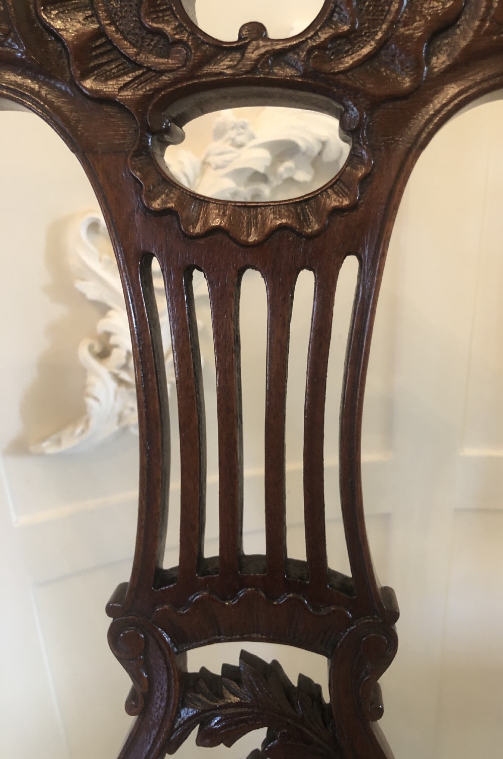 A set of four dark mahogany Victorian dining chairs featuring openwork carved back splats, cabriole front legs, and seats upholstered in a monochrome floral fabric. View X