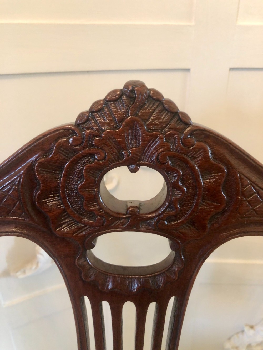 A set of four dark mahogany Victorian dining chairs featuring openwork carved back splats, cabriole front legs, and seats upholstered in a monochrome floral fabric. View XII