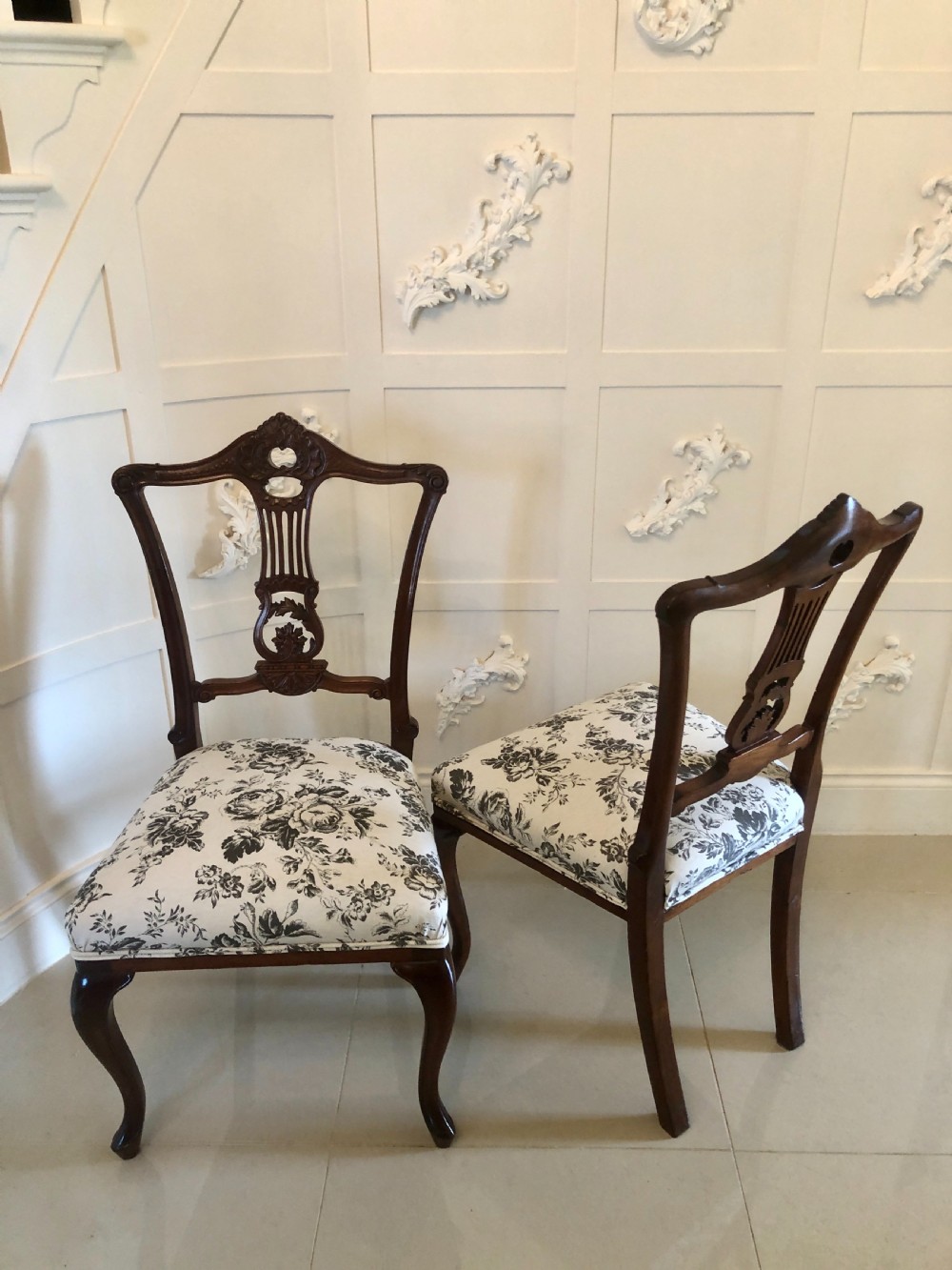 A set of four dark mahogany Victorian dining chairs featuring openwork carved back splats, cabriole front legs, and seats upholstered in a monochrome floral fabric. View XIII