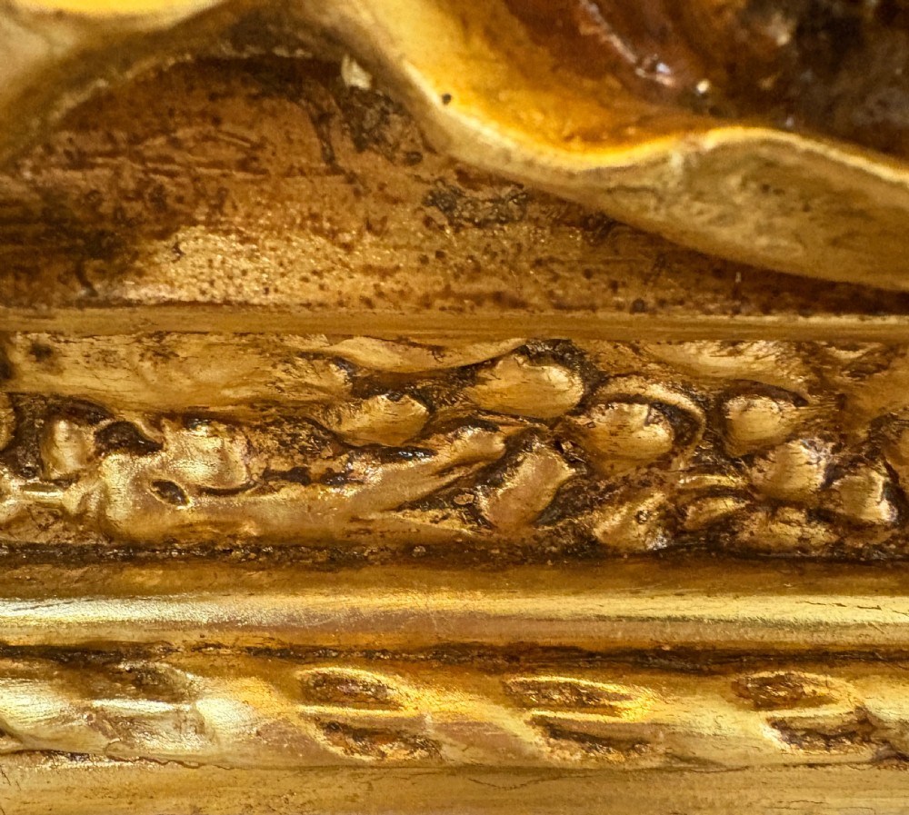 A large rectangular wall mirror featuring an ornate gilded frame decorated with carved floral scrolls and two cherub figures atop the crest. View II