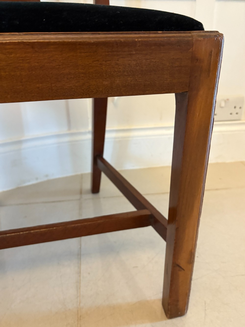 A set of eight Edwardian mahogany dining chairs with carved ribbon-pierced splats and black upholstered drop-in seats, including two armchairs. View V