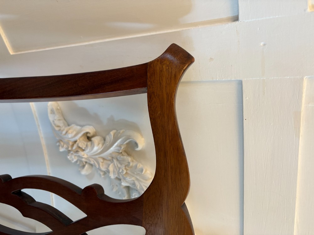 A set of eight Edwardian mahogany dining chairs with carved ribbon-pierced splats and black upholstered drop-in seats, including two armchairs. View XI