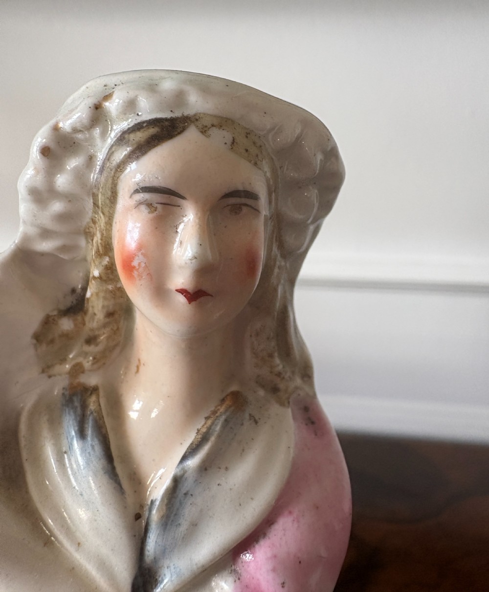Victorian Staffordshire earthenware figurine depicting a man in a tartan kilt holding a child next to a woman, painted in polychrome glazes on a moulded base. View V