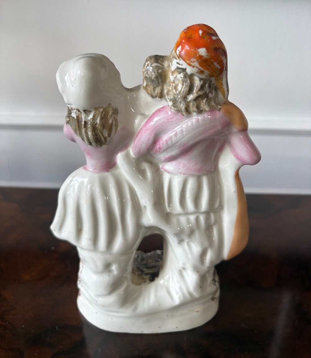 Victorian Staffordshire earthenware figurine depicting a man in a tartan kilt holding a child next to a woman, painted in polychrome glazes on a moulded base. View VIII