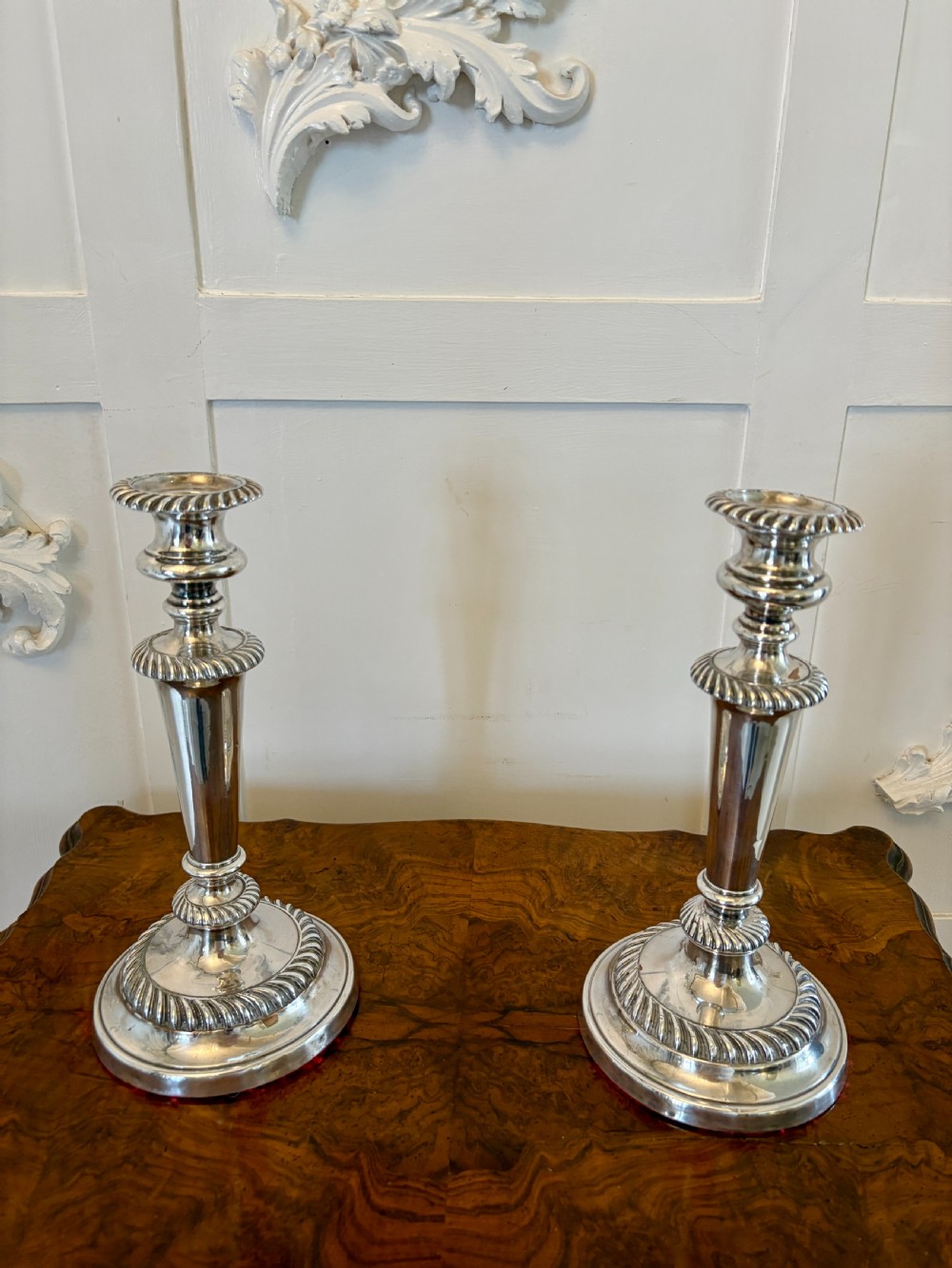 A pair of Victorian silver-plated candlesticks featuring gadrooned borders, stepped circular bases, and tapered shafts.