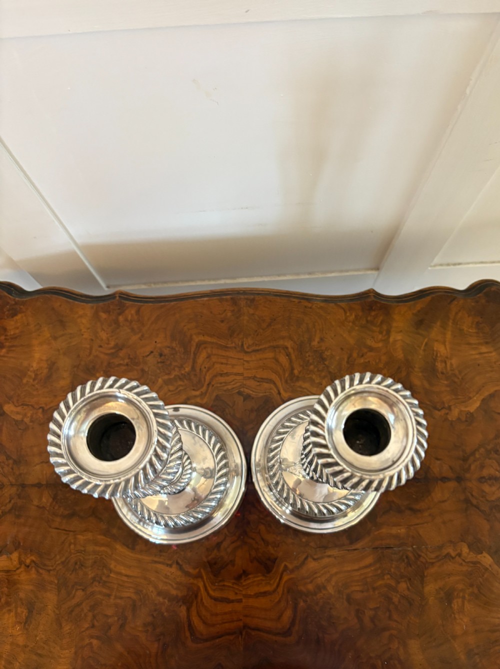 A pair of Victorian silver-plated candlesticks featuring gadrooned borders, stepped circular bases, and tapered shafts. View VII