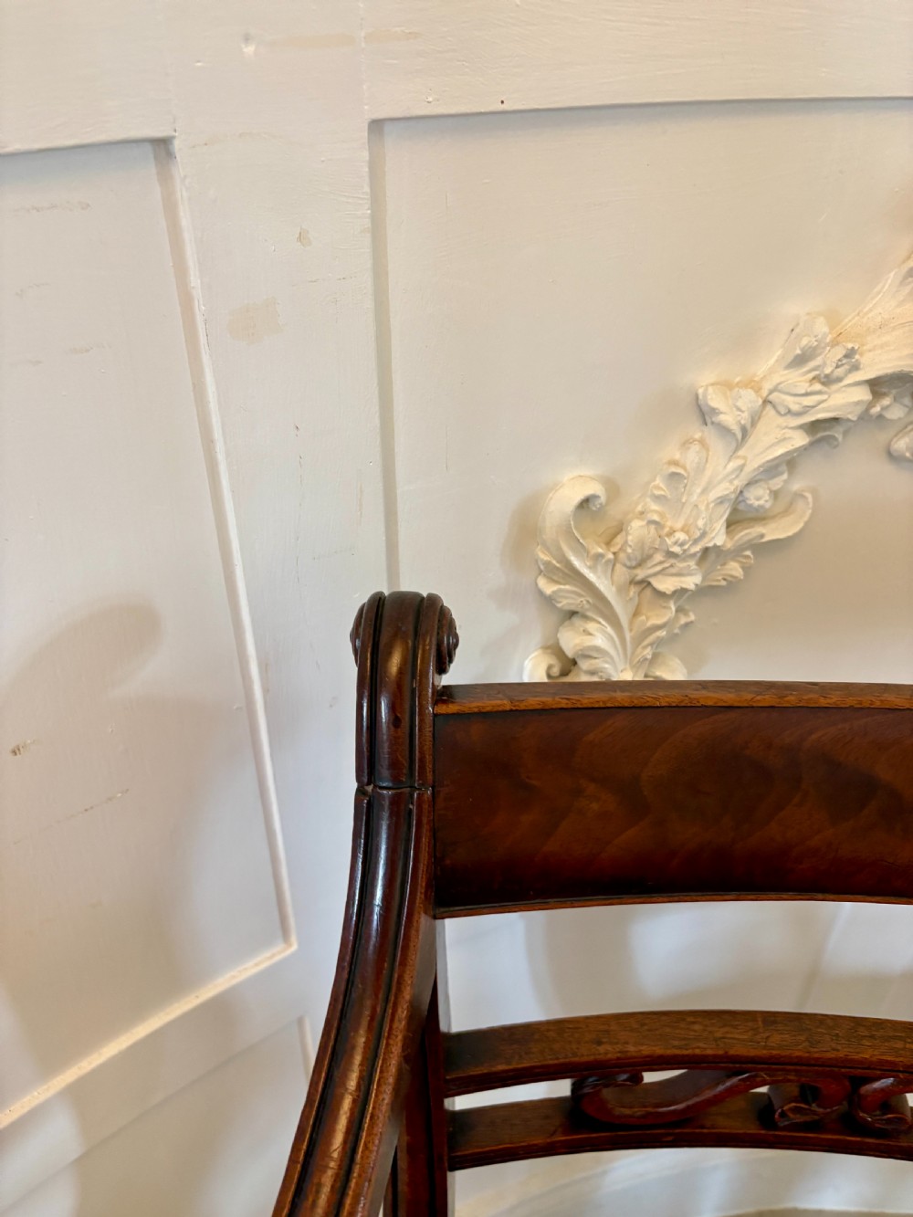 A pair of George III mahogany desk chairs featuring scroll arms, carved back splats, turned front legs, and red leather seats. View IX
