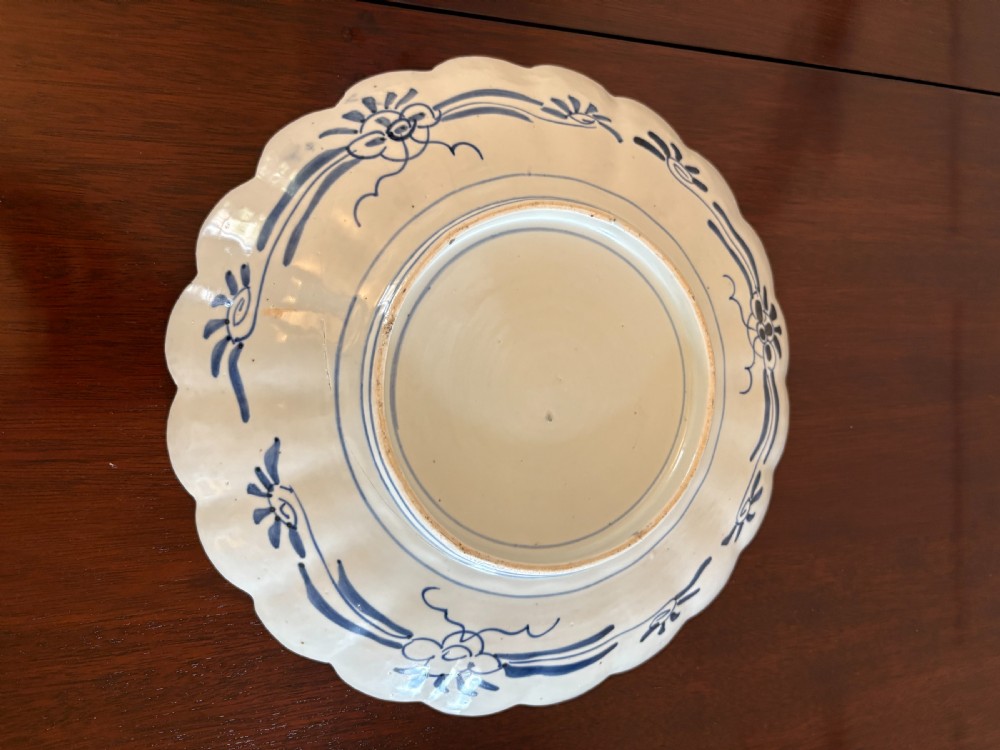 A pair of circular Japanese Imari porcelain plates with scalloped edges, decorated in hand-painted orange, terracotta, blue, and gold floral patterns. View II