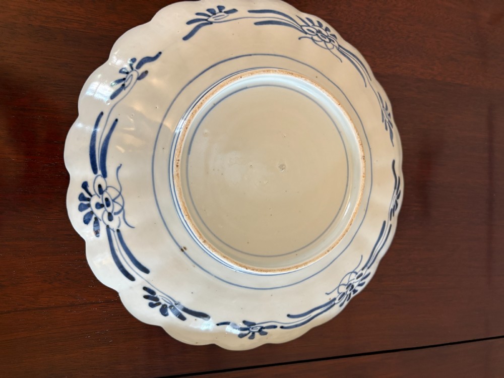 A pair of circular Japanese Imari porcelain plates with scalloped edges, decorated in hand-painted orange, terracotta, blue, and gold floral patterns. View III