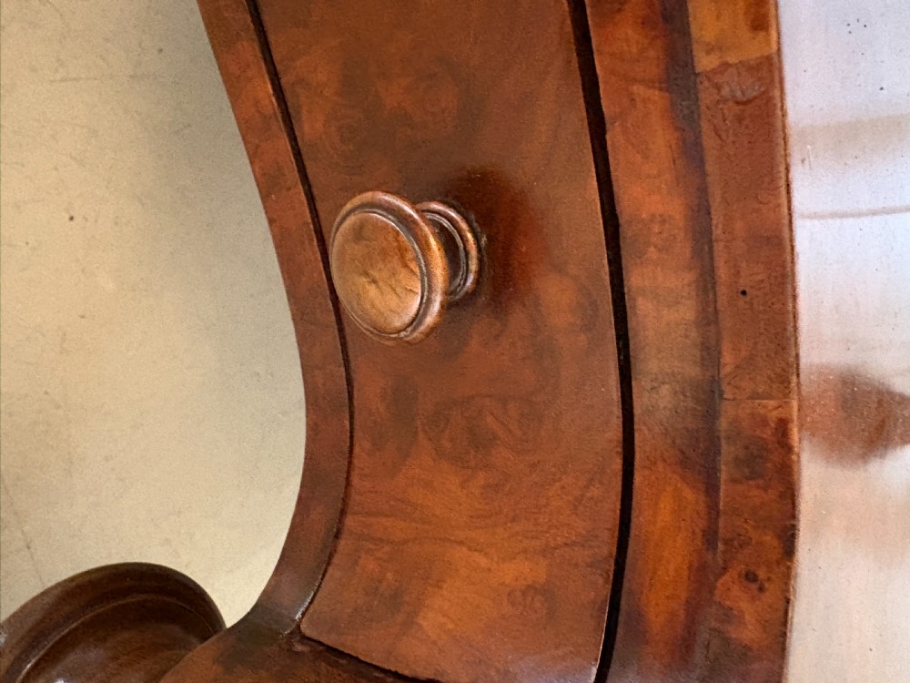 A Victorian three-tiered burr walnut whatnot featuring serpentine shelves, turned spindle supports, a pierced brass top gallery, and a base drawer on brass castors. View VII
