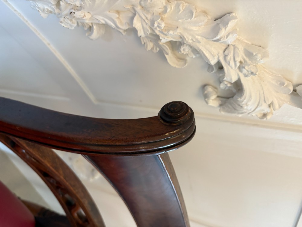 A set of four George III mahogany dining chairs with carved scroll backrests, red leather upholstery, and turned front legs. View VII
