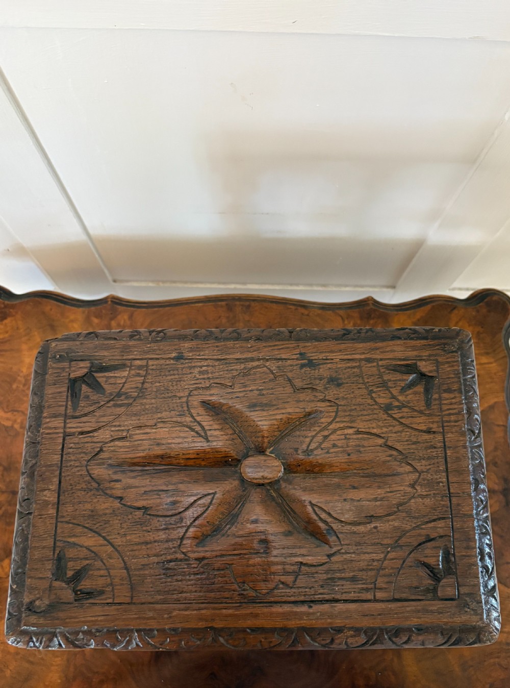 A dark carved oak miniature table with a central carved flower motif on top, carved frieze edges, turned legs, and a barley twist cross stretcher. View IX