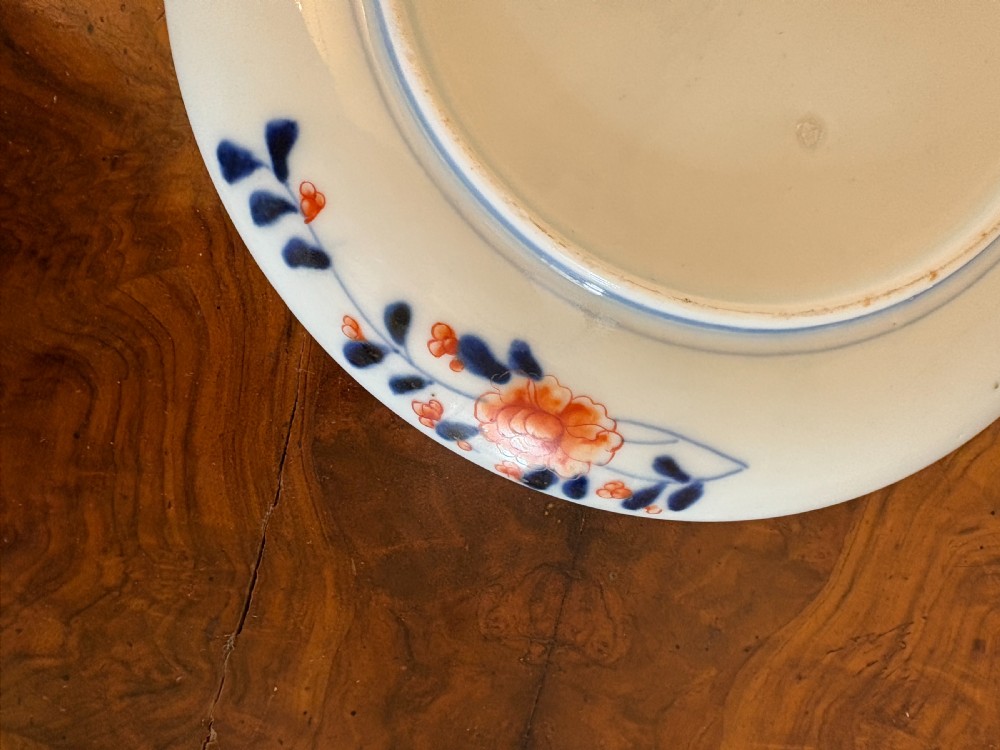 A circular antique Japanese Imari porcelain plate hand-painted with intricate cobalt blue, rust-red, and gilt floral patterns. View II