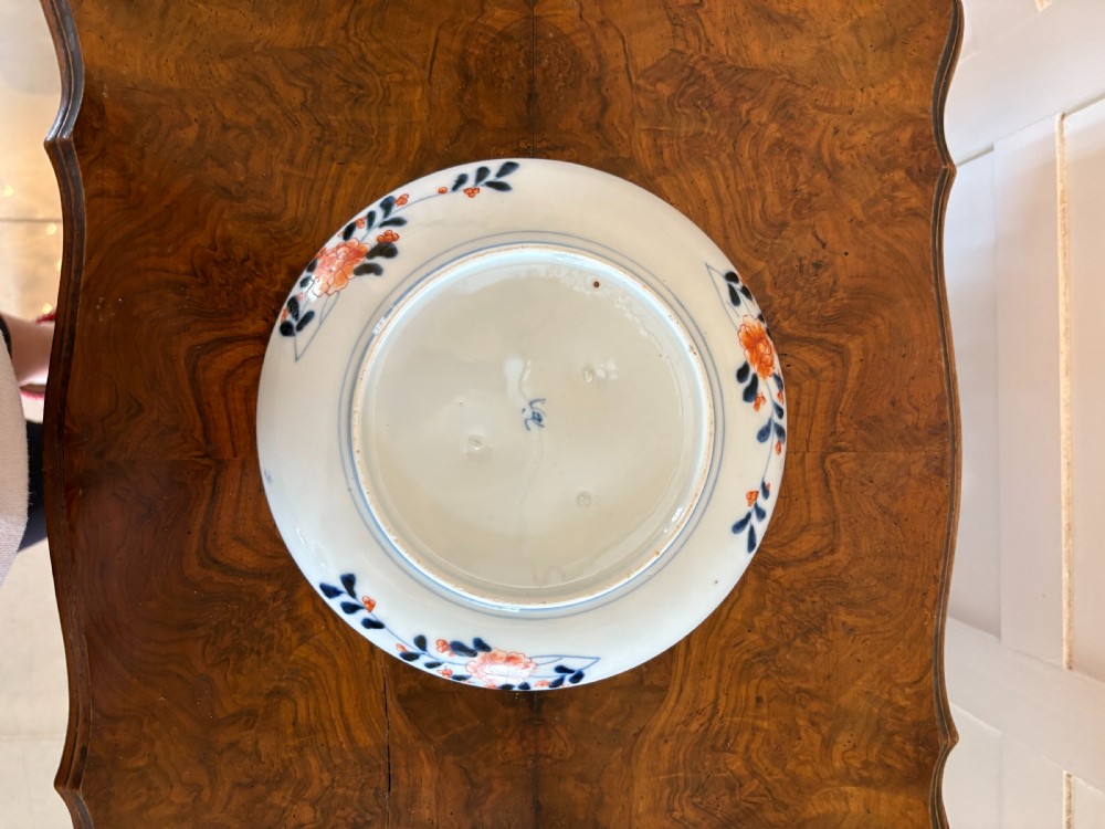 A circular antique Japanese Imari porcelain plate hand-painted with intricate cobalt blue, rust-red, and gilt floral patterns. View V