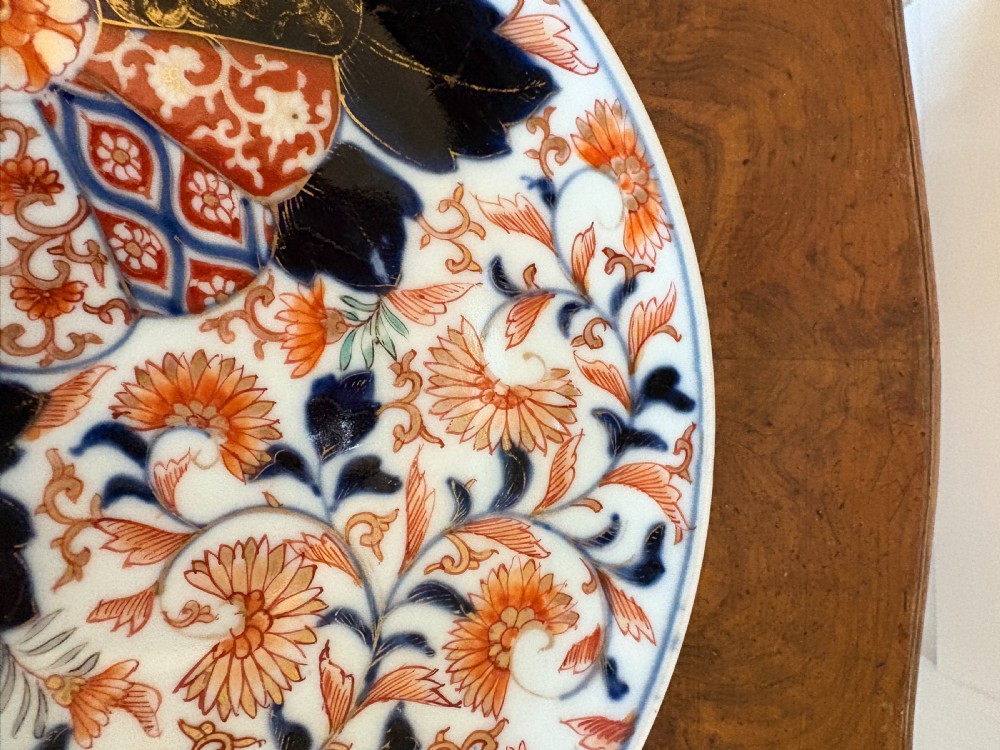 A circular antique Japanese Imari porcelain plate hand-painted with intricate cobalt blue, rust-red, and gilt floral patterns. View VII