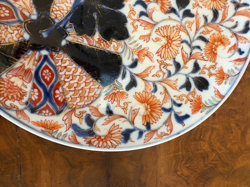 A circular antique Japanese Imari porcelain plate hand-painted with intricate cobalt blue, rust-red, and gilt floral patterns. View VIII