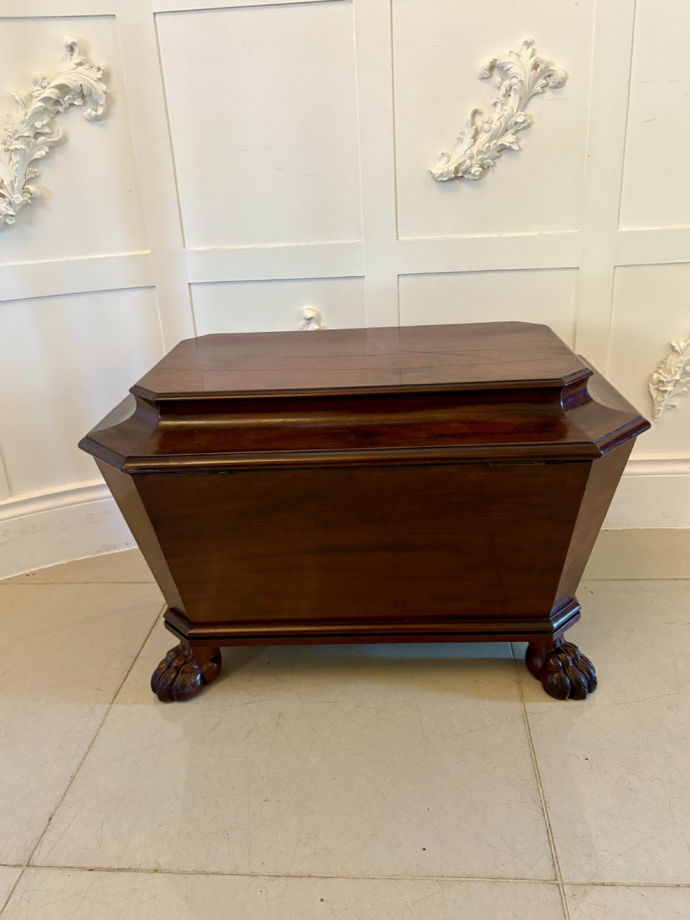 A Regency mahogany wine cooler shaped as a classical sarcophagus with figured wood panels, a central brass keyhole, and carved lion paw feet. View III
