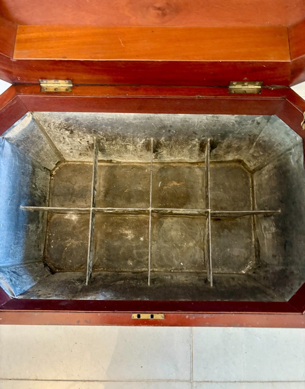 A Regency mahogany wine cooler shaped as a classical sarcophagus with figured wood panels, a central brass keyhole, and carved lion paw feet. View VI