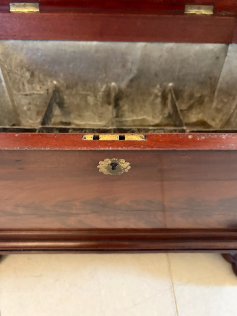 A Regency mahogany wine cooler shaped as a classical sarcophagus with figured wood panels, a central brass keyhole, and carved lion paw feet. View VII