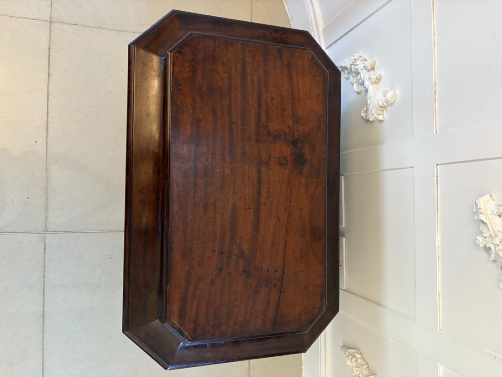 A Regency mahogany wine cooler shaped as a classical sarcophagus with figured wood panels, a central brass keyhole, and carved lion paw feet. View XV
