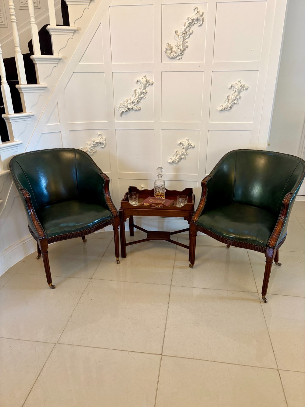 An Edwardian mahogany butlers tray featuring scalloped gallery sides with cut-out handles, resting on a matching wooden stand with reeded legs and cross-stretchers. View IX