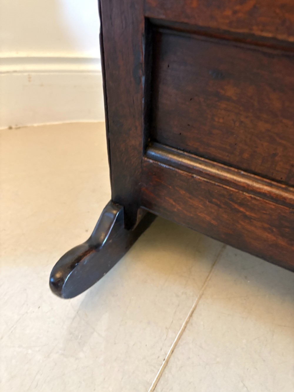 A dark oak panelled rocking crib featuring a hooded end, raised corner finials, and curved rocking runners. View VIII