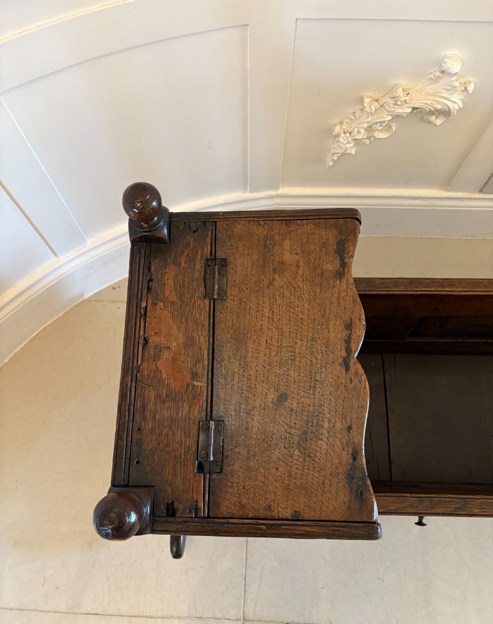 A dark oak panelled rocking crib featuring a hooded end, raised corner finials, and curved rocking runners. View XI