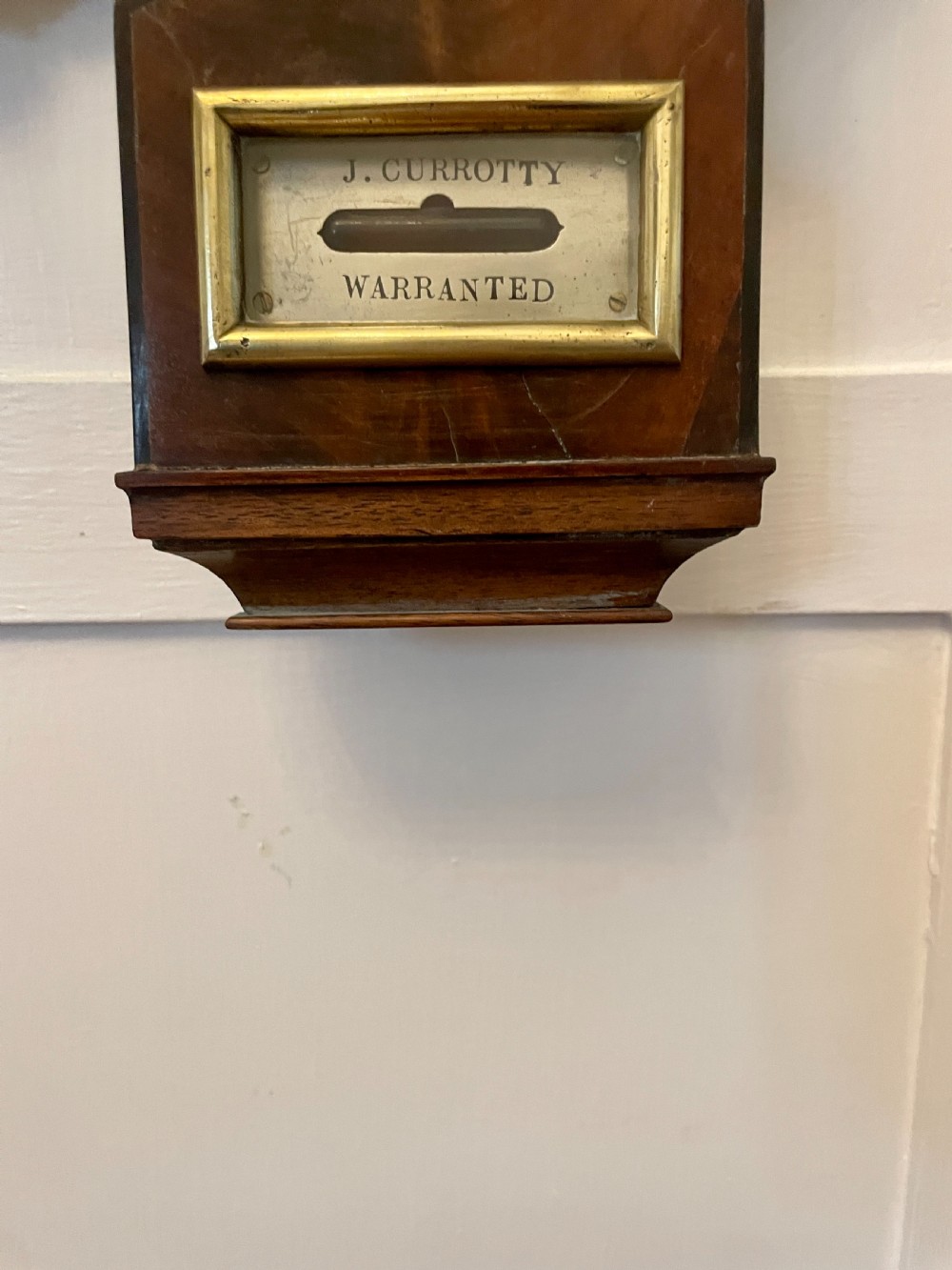 A vertical George III mahogany banjo barometer featuring a pediment top, glass thermometer tube, silvered dial, and brass bezel. View II