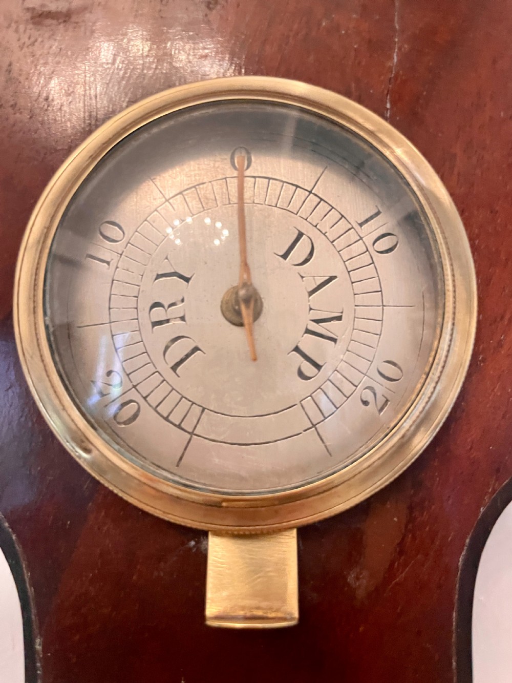 A vertical George III mahogany banjo barometer featuring a pediment top, glass thermometer tube, silvered dial, and brass bezel. View III