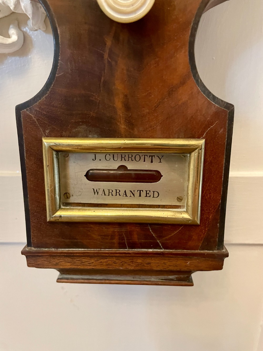 A vertical George III mahogany banjo barometer featuring a pediment top, glass thermometer tube, silvered dial, and brass bezel. View VIII