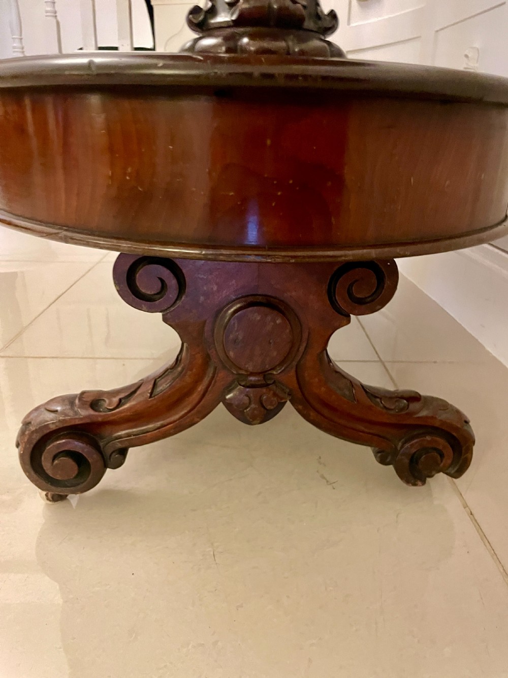 An oval dark mahogany two-tiered serving table featuring turned support columns, metal scroll handles, and carved feet with casters. View VIII