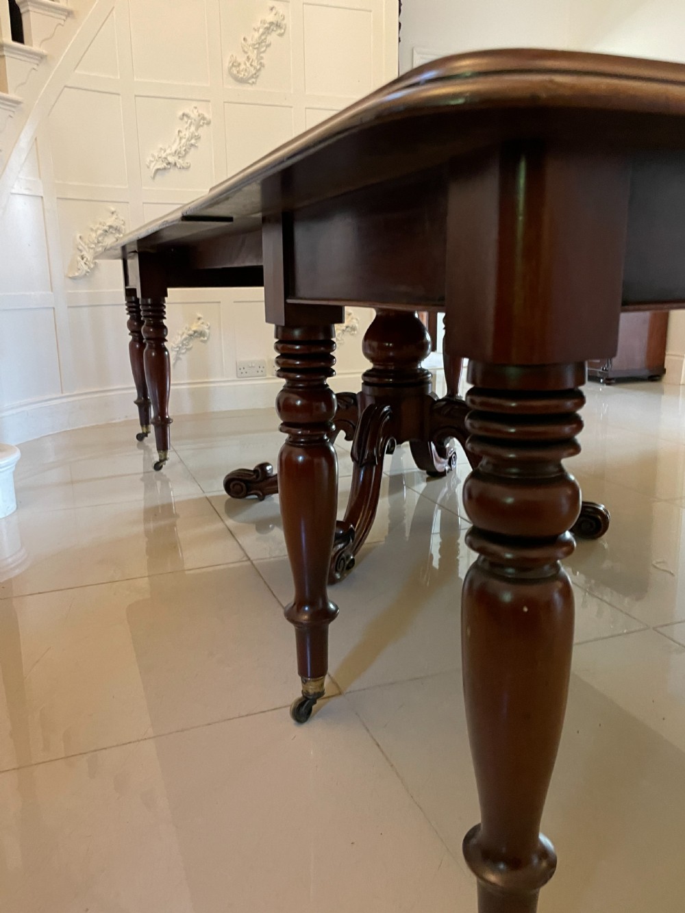 A large Victorian extending mahogany dining table featuring turned legs fitted with brass castors and a polished top with rounded corners. View XIII