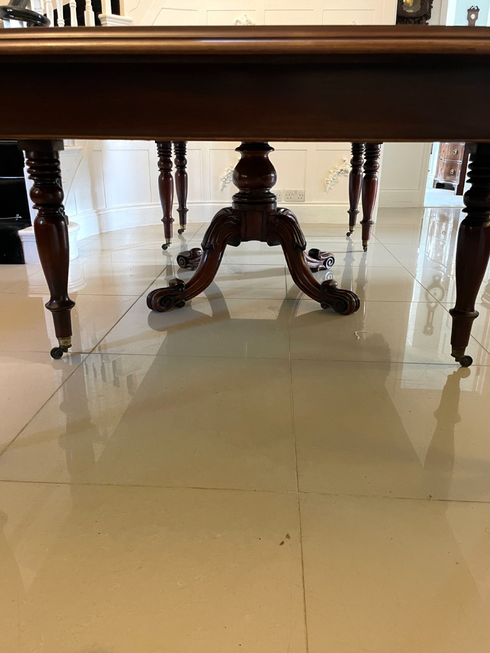A large Victorian extending mahogany dining table featuring turned legs fitted with brass castors and a polished top with rounded corners. View XIV